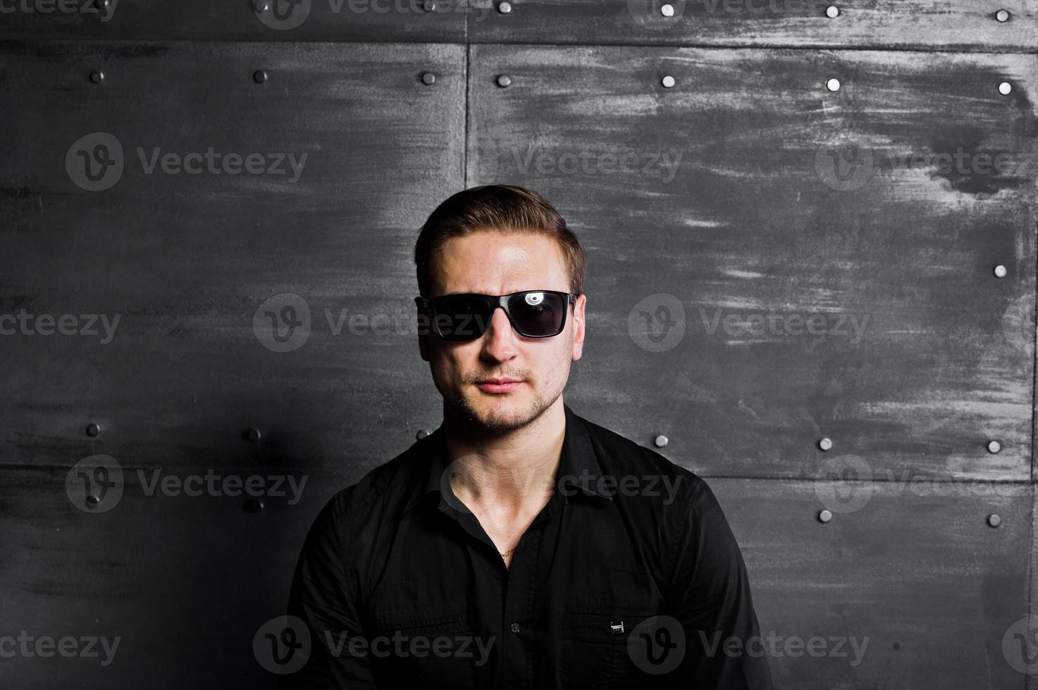 retrato de estudio de hombre elegante vestido con camisa negra y gafas contra la pared de acero. foto