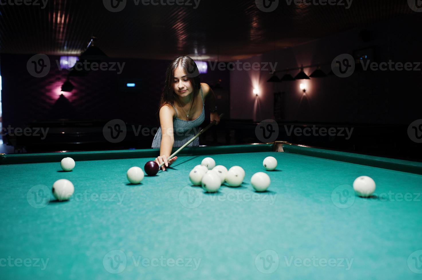 retrato de una atractiva joven vestida jugando al billar. foto