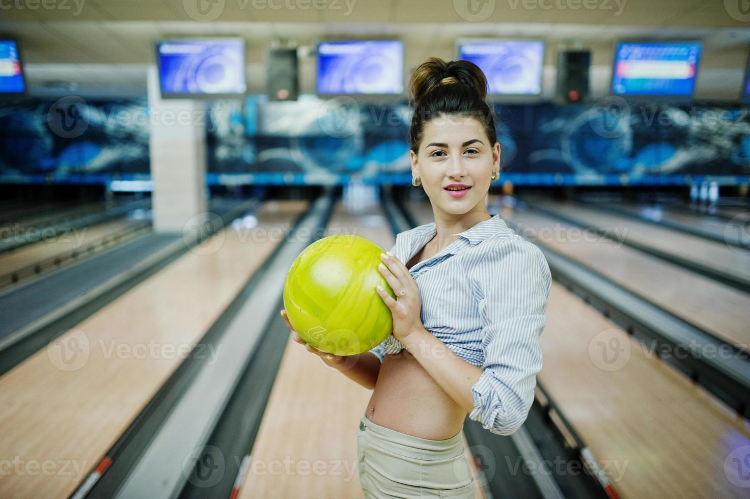 Girl with bowling ball on alley played at bowling club. photo