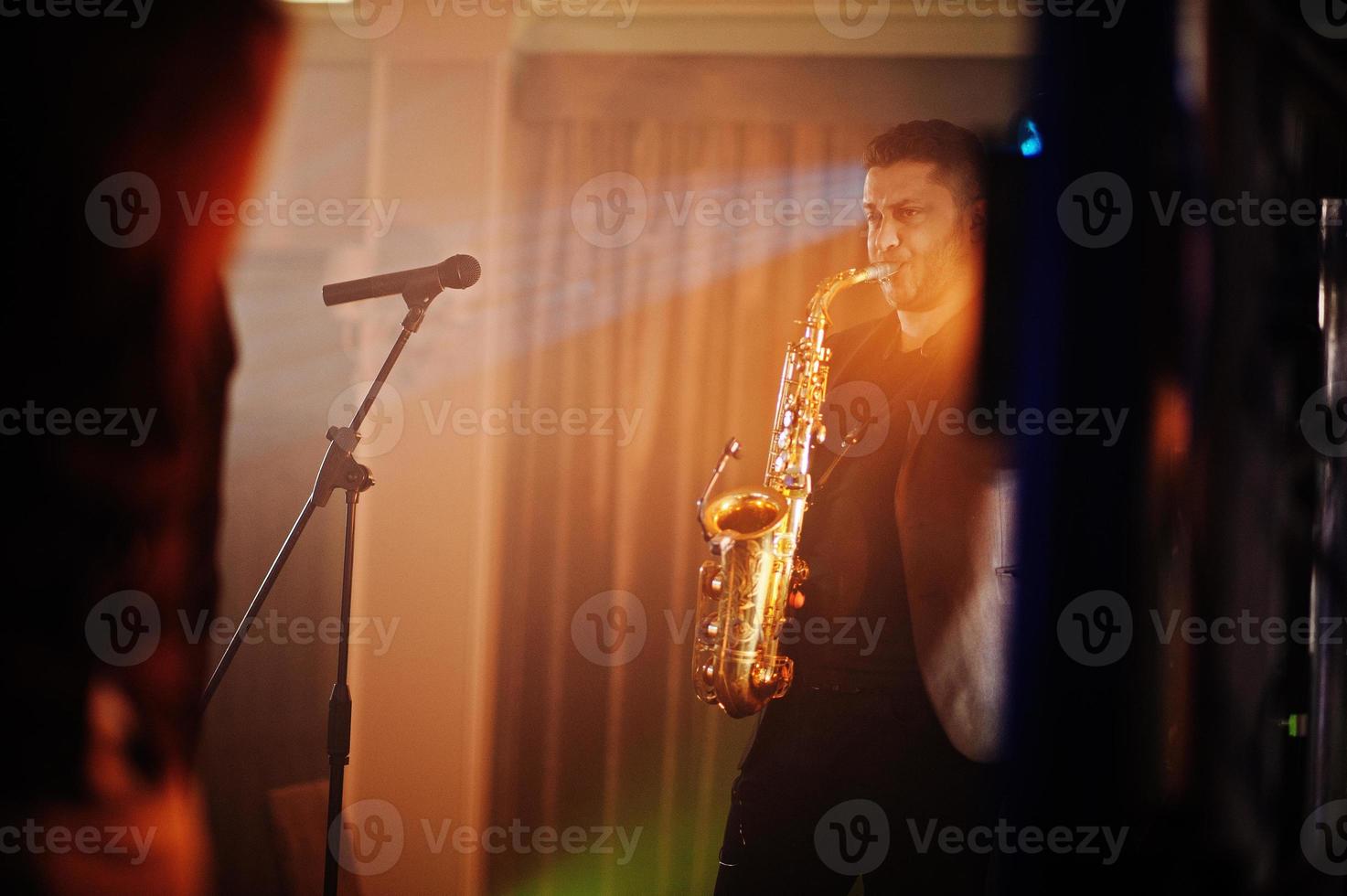 Musicial music live band performing on a stage with different lights. Saxophonist plays. photo