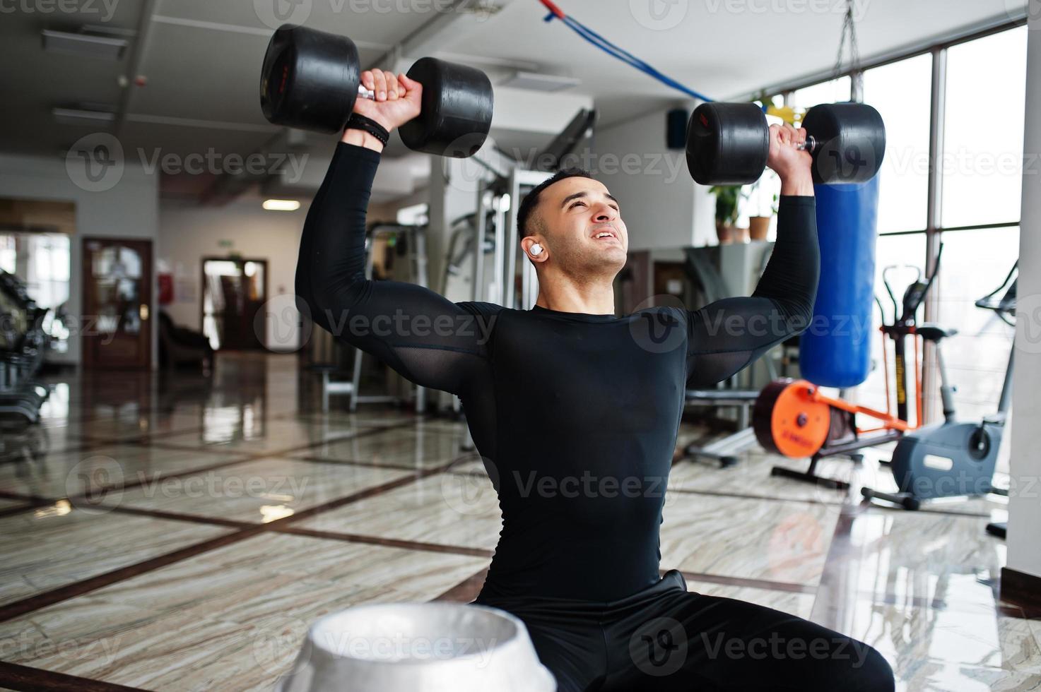 Muscular arab man training with dumbbells in modern gym. photo