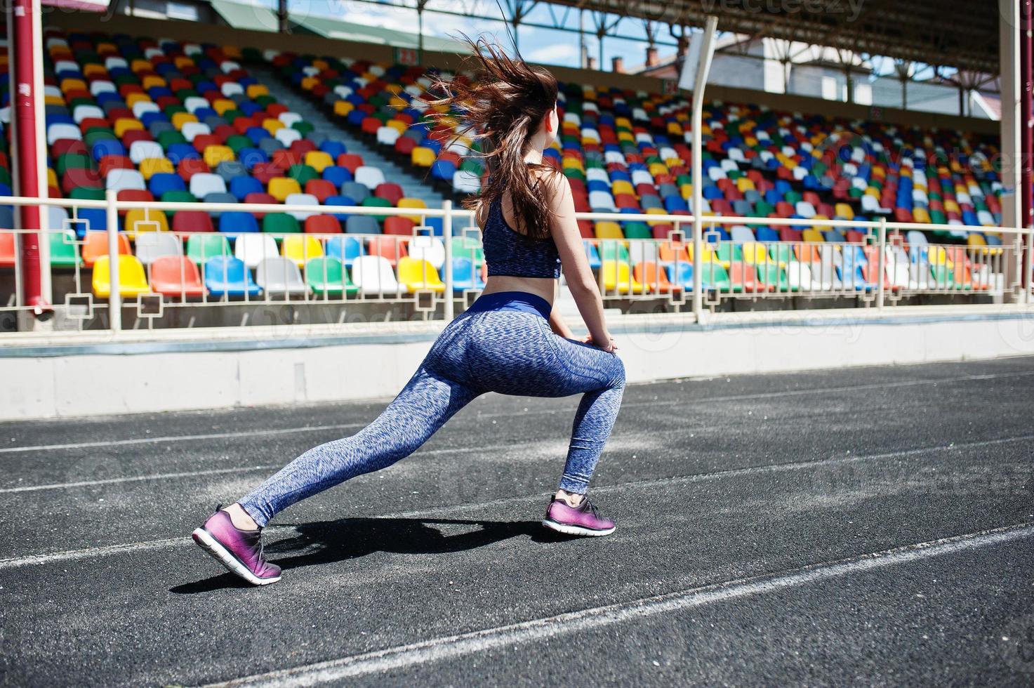 Portrait of an attractive fit woman doing exercises for her legs in the stadium. photo