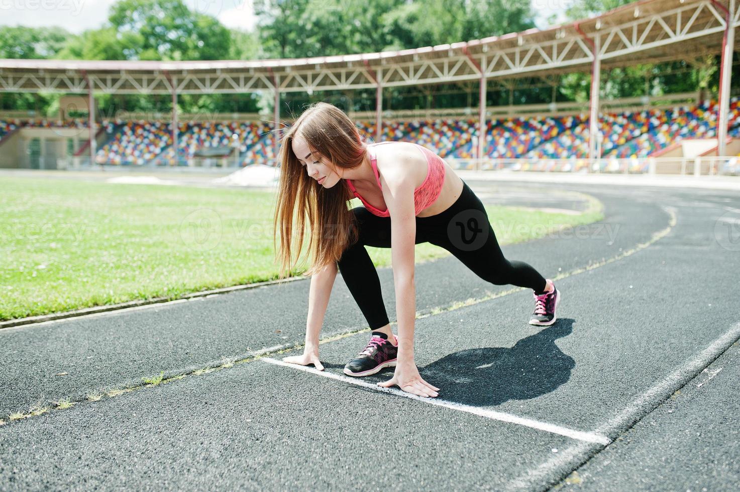 Fitness sporty girl in sportswear at stadium outdoor sports. Happy sexy woman running on athletic track treadmill on stadium. photo