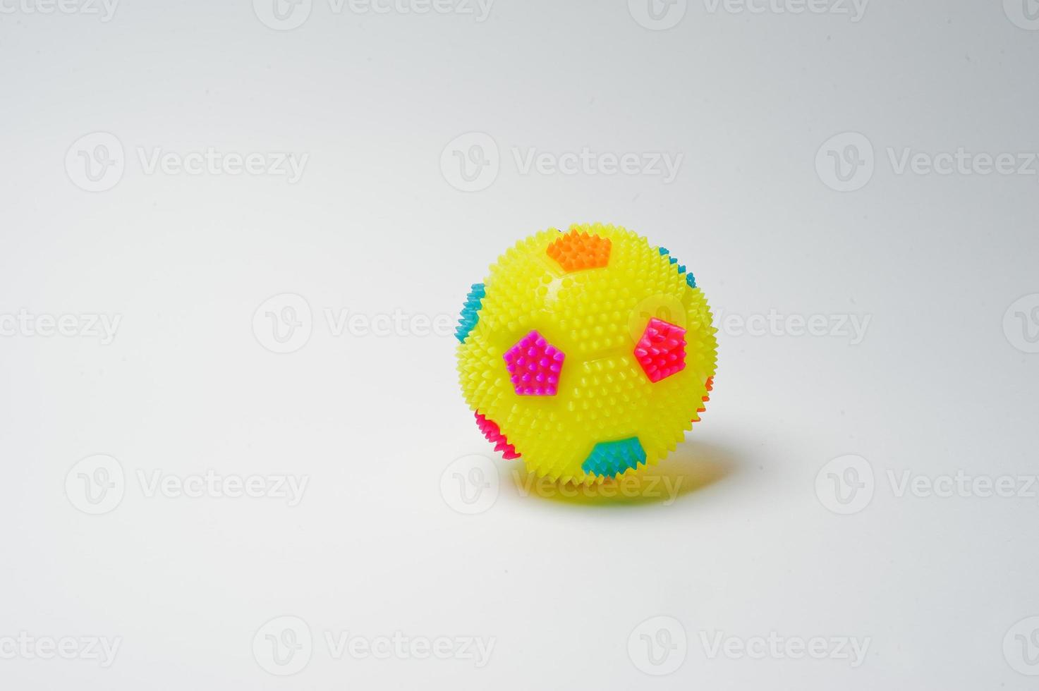 Close-up photo of a small yellow ball on a white background.