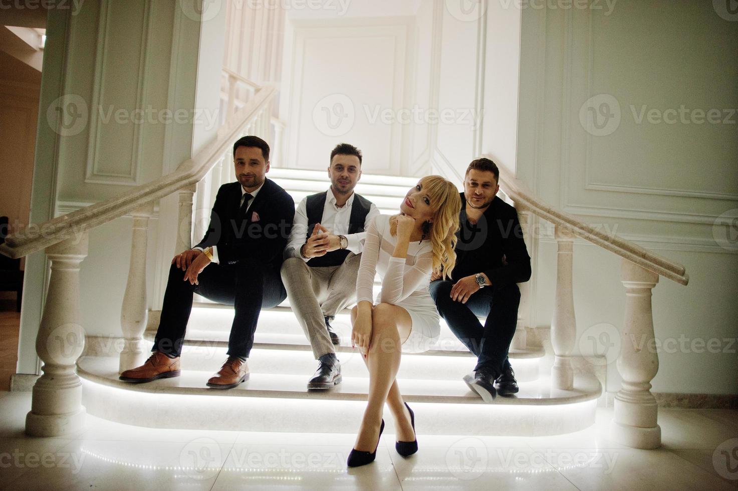 Three stylish bearded man well dressed with one blonde girl in white dress posed. Musician band or singers. photo