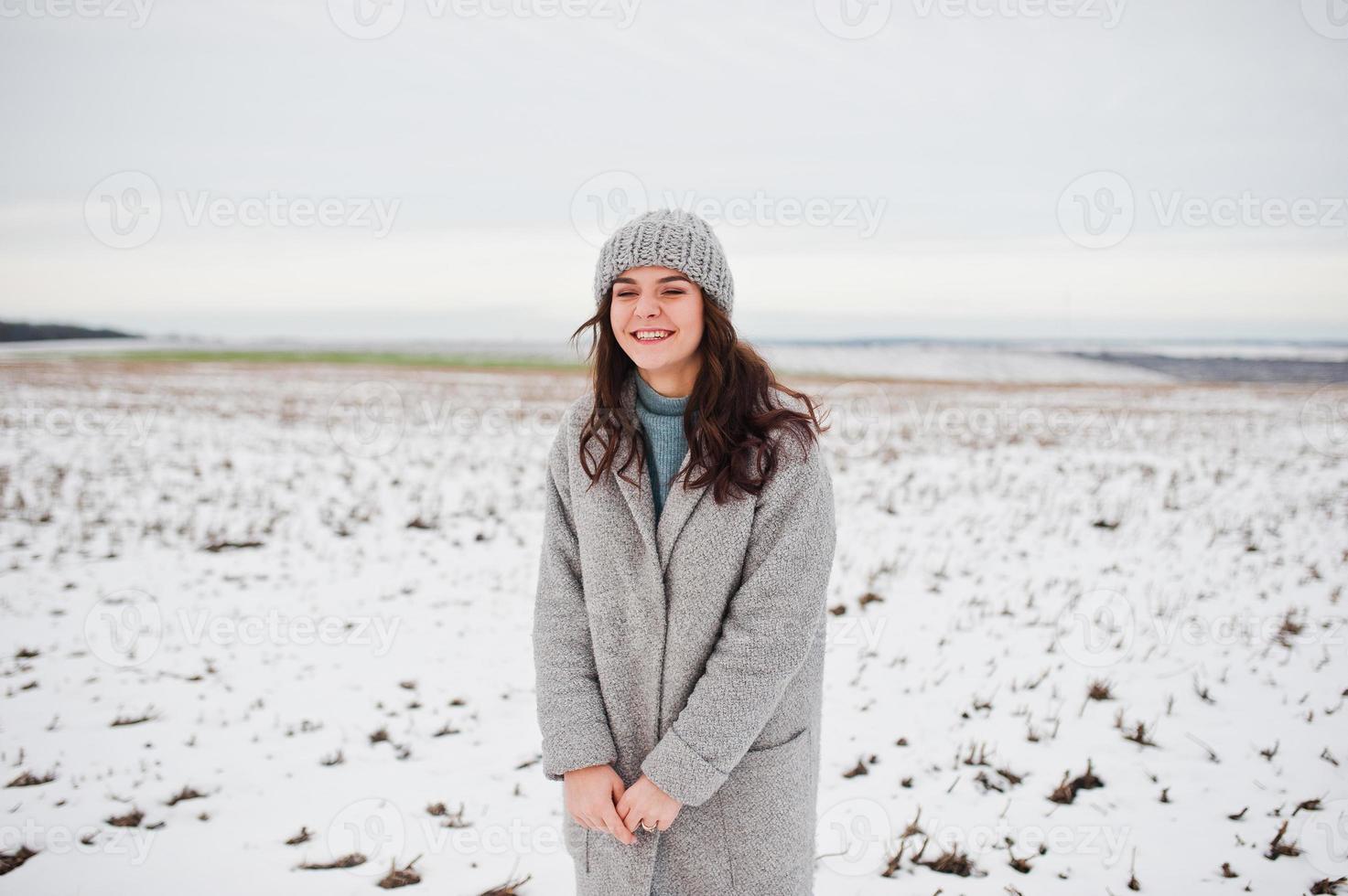 Gentle girl in gray coat and hat against snow landscape. photo