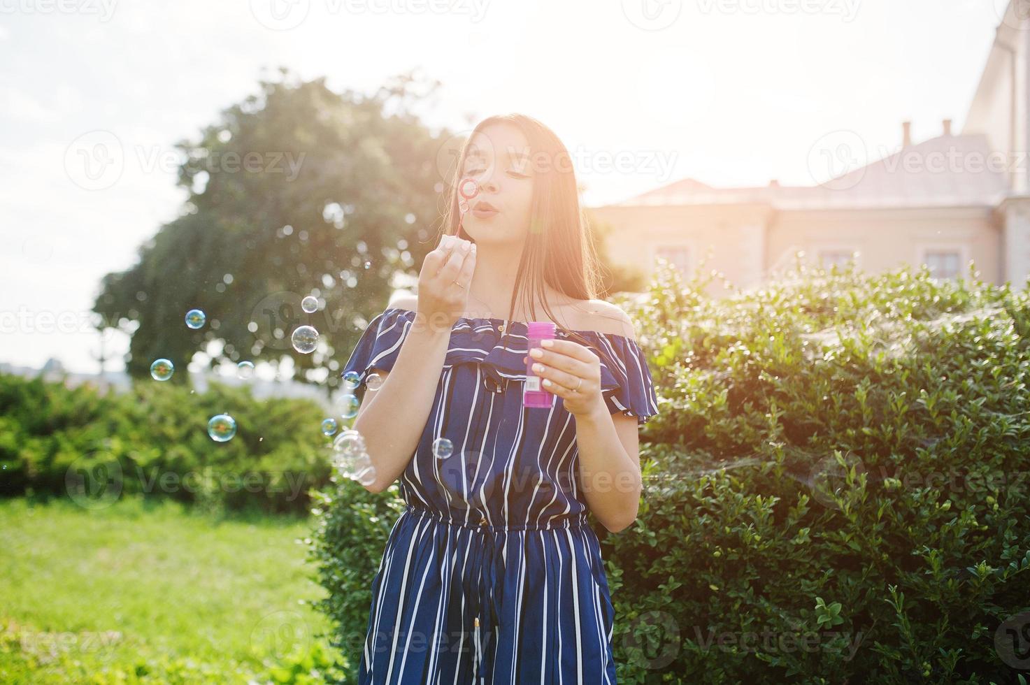Gorgeous brunette girl at street of city lets out soap bubbles. photo