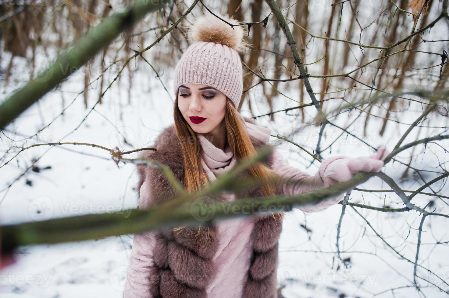 chica elegante con abrigo de piel y sombreros en el bosque de invierno. foto