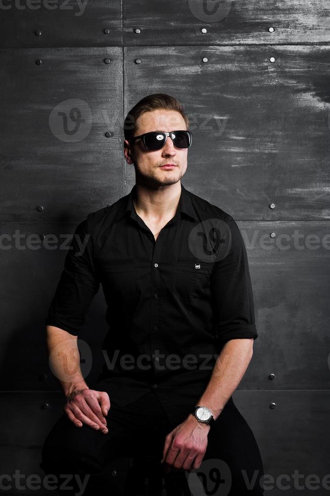 Studio portrait of stylish man wear on black shirt and glasses against steel wall. photo
