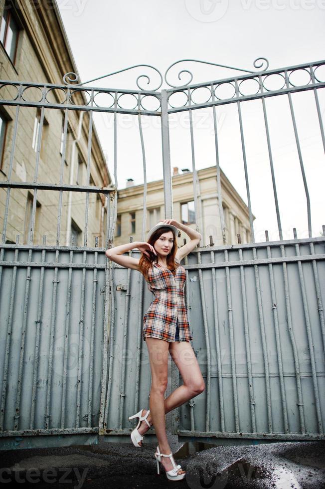 Amazing long legs with hig heels girl wear on hat against iron fence. photo