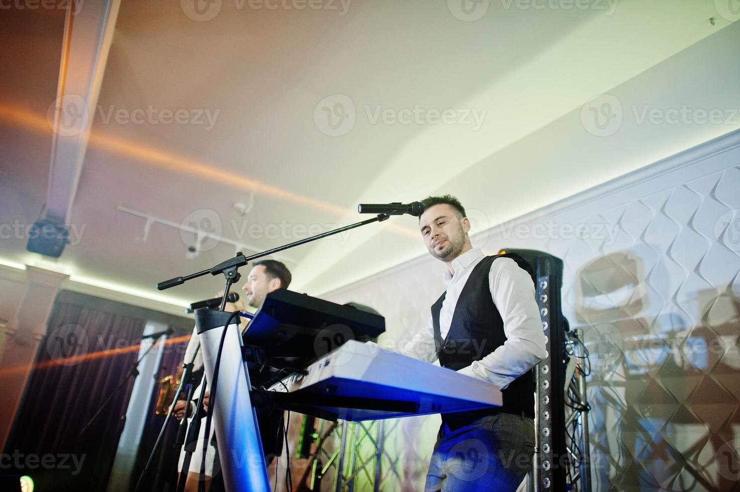 Musicial music live band performing on a stage with different lights. Keyboardist play. photo