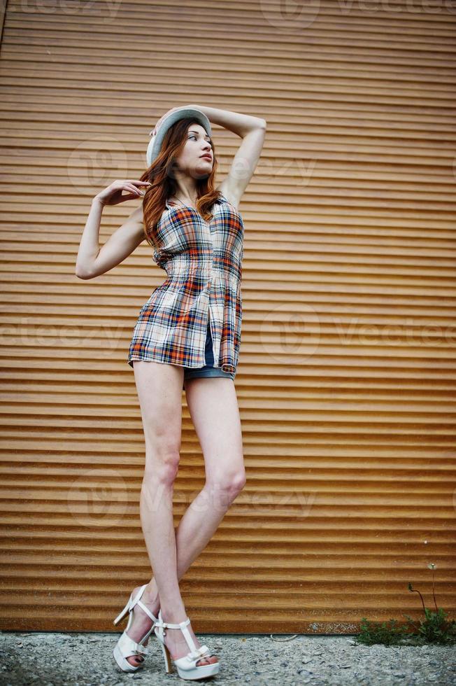 Amazing long legs with hig heels girl wear on hat against shutter. photo