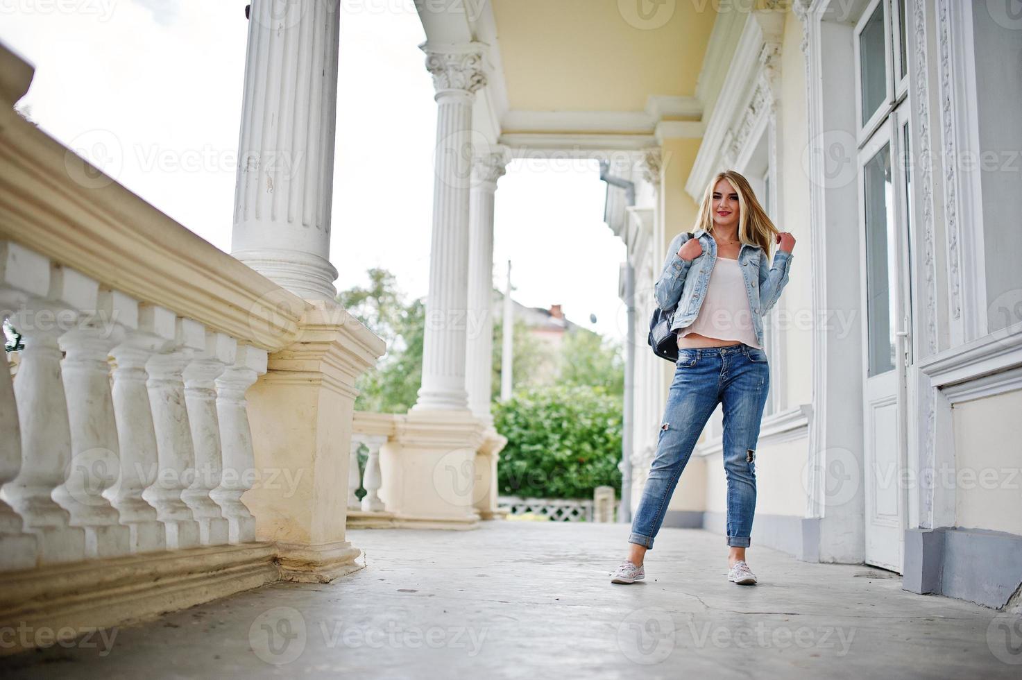 ropa de chica rubia en jeans con mochila posada contra casa vintage. foto