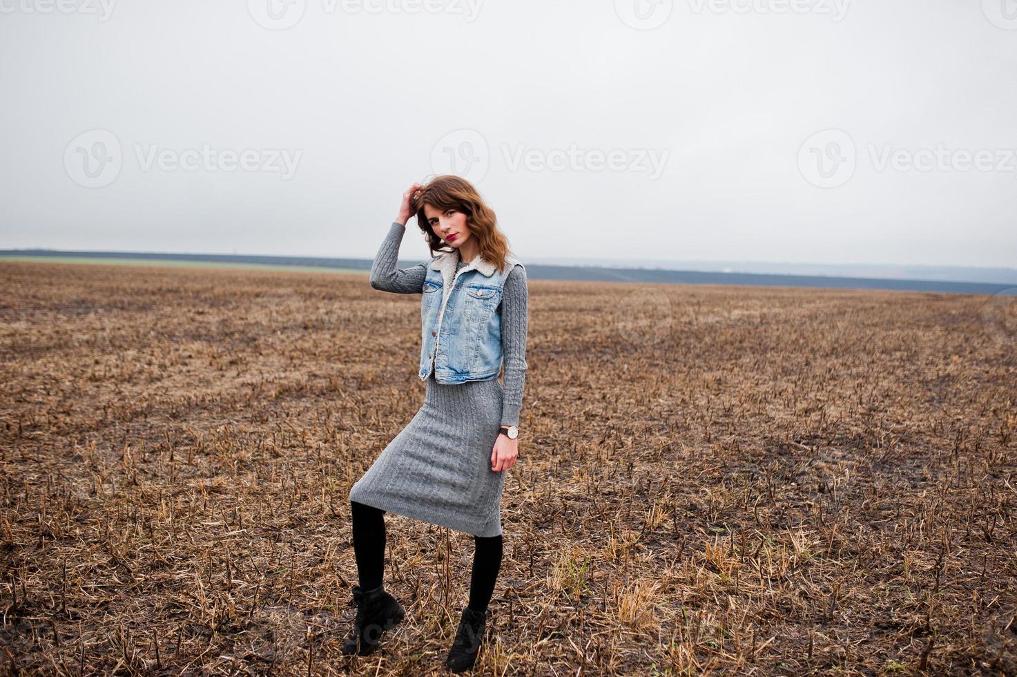 Portrait of brunette curly girl in jeans jacket at field. photo