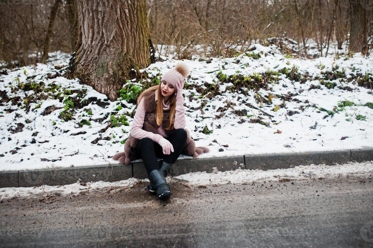 chica elegante con abrigo de piel y sombreros en el día de invierno en el borde de la carretera. foto