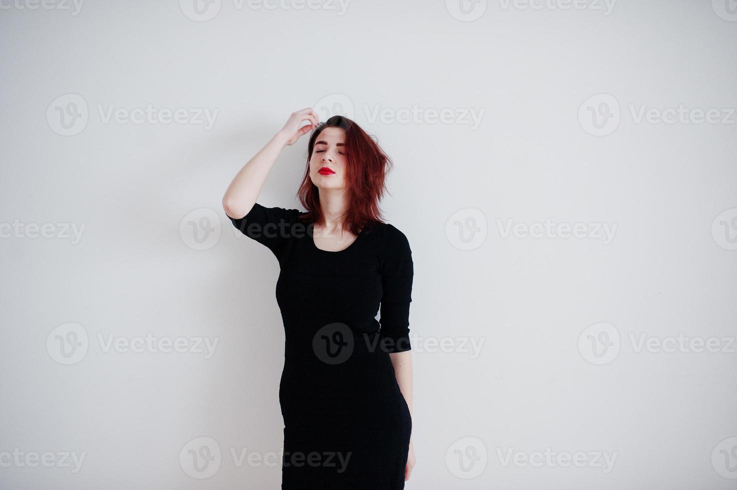 Red haired girl on black dress tunic against white wall at empty room. photo