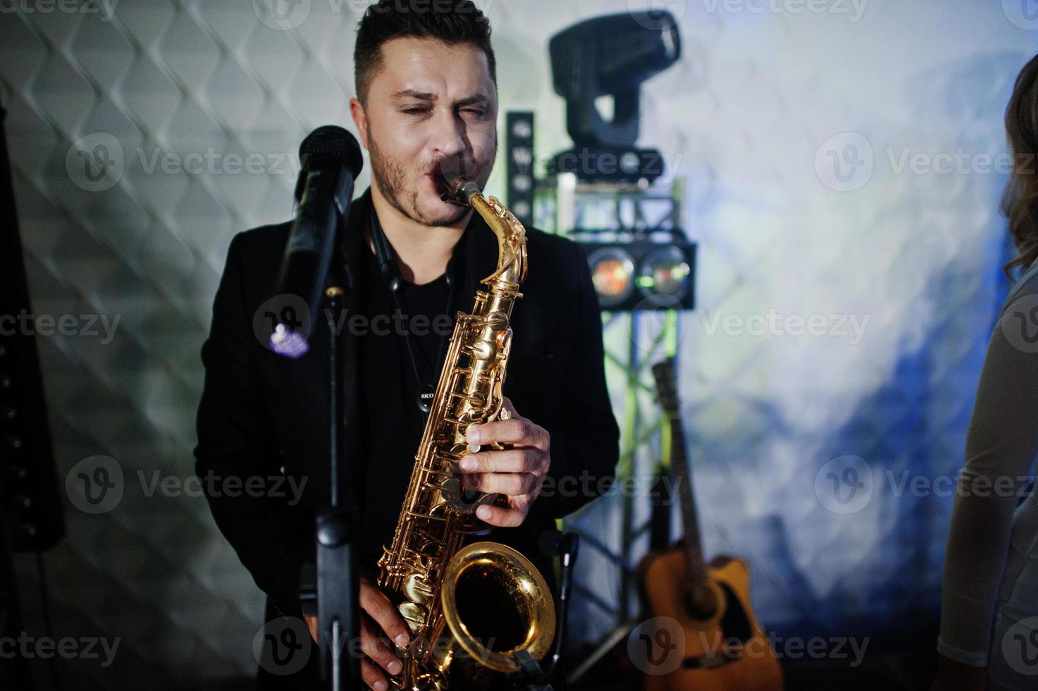Musicial music live band performing on a stage with different lights. Saxophonist plays. photo