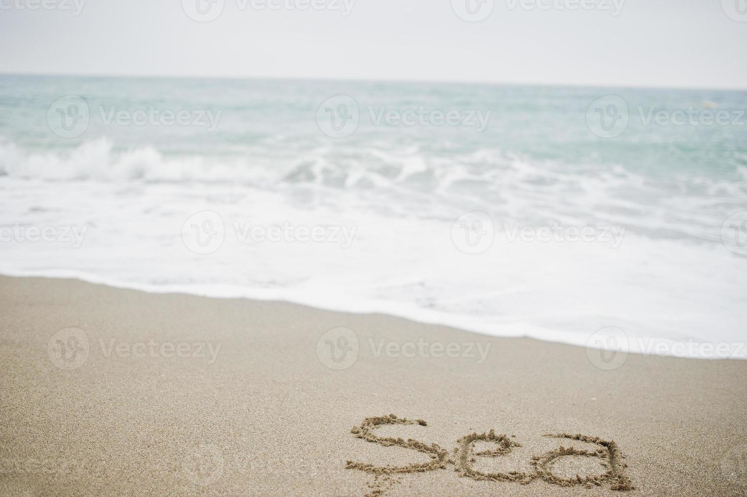 Close-up photo of sand inscription sea by the foamy waves.