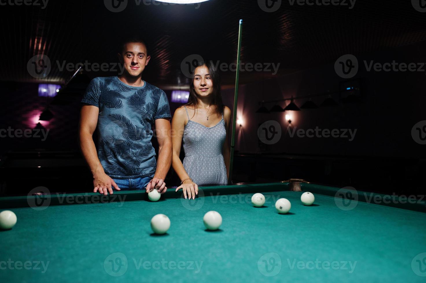 Woman in dress playing pool with a man in a pub. photo