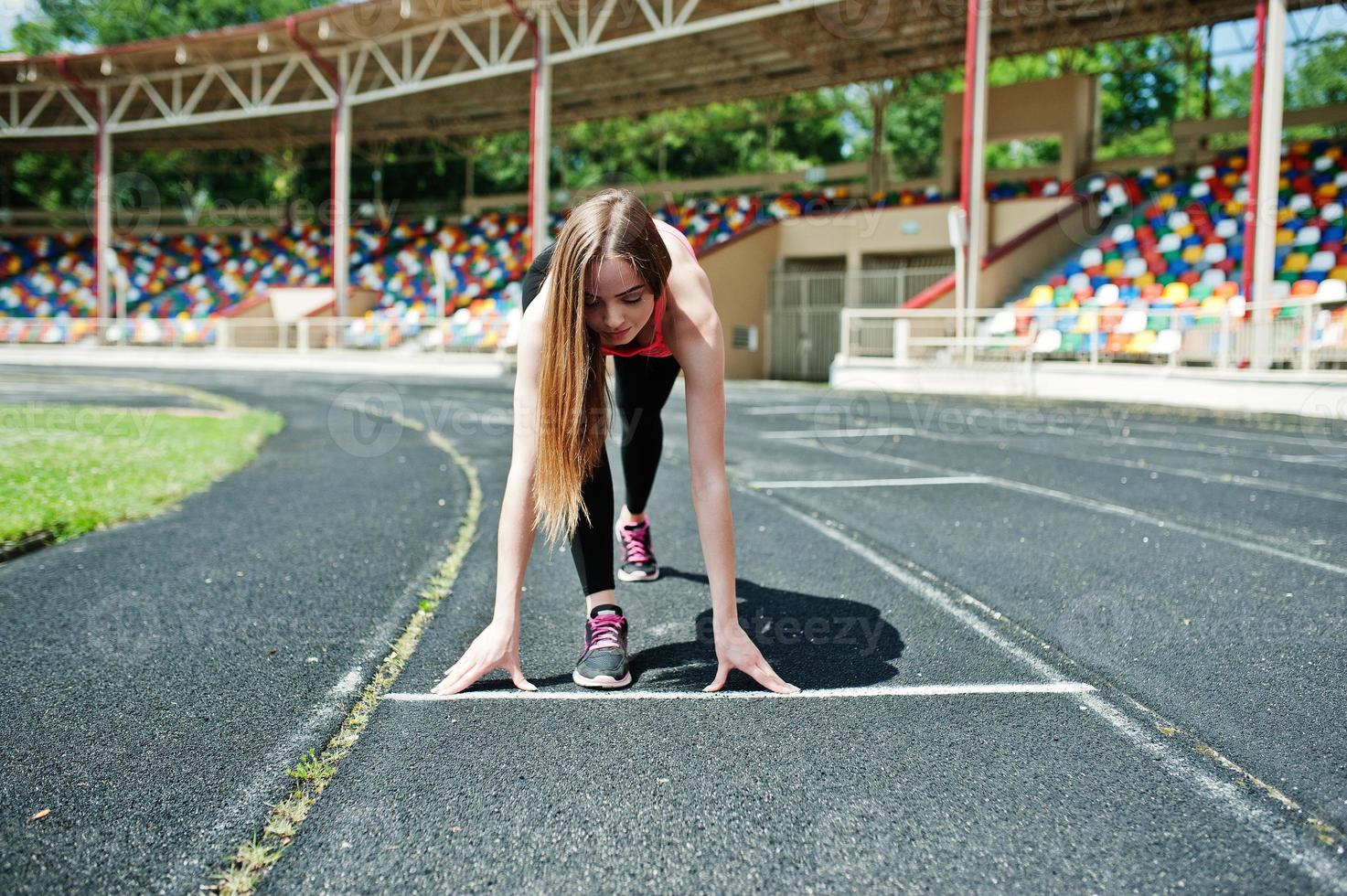 Fitness sporty girl in sportswear at stadium outdoor sports. Happy sexy woman running on athletic track treadmill on stadium. photo