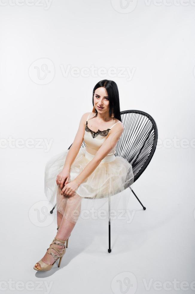 Portrait of brunette girl on beige dress with chair isolated on white. photo