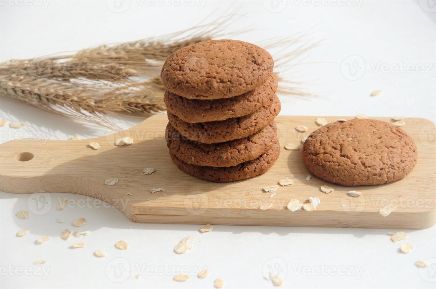 biscuits on a wooden board with oatmeal flakes on a white background, banner, view from above photo