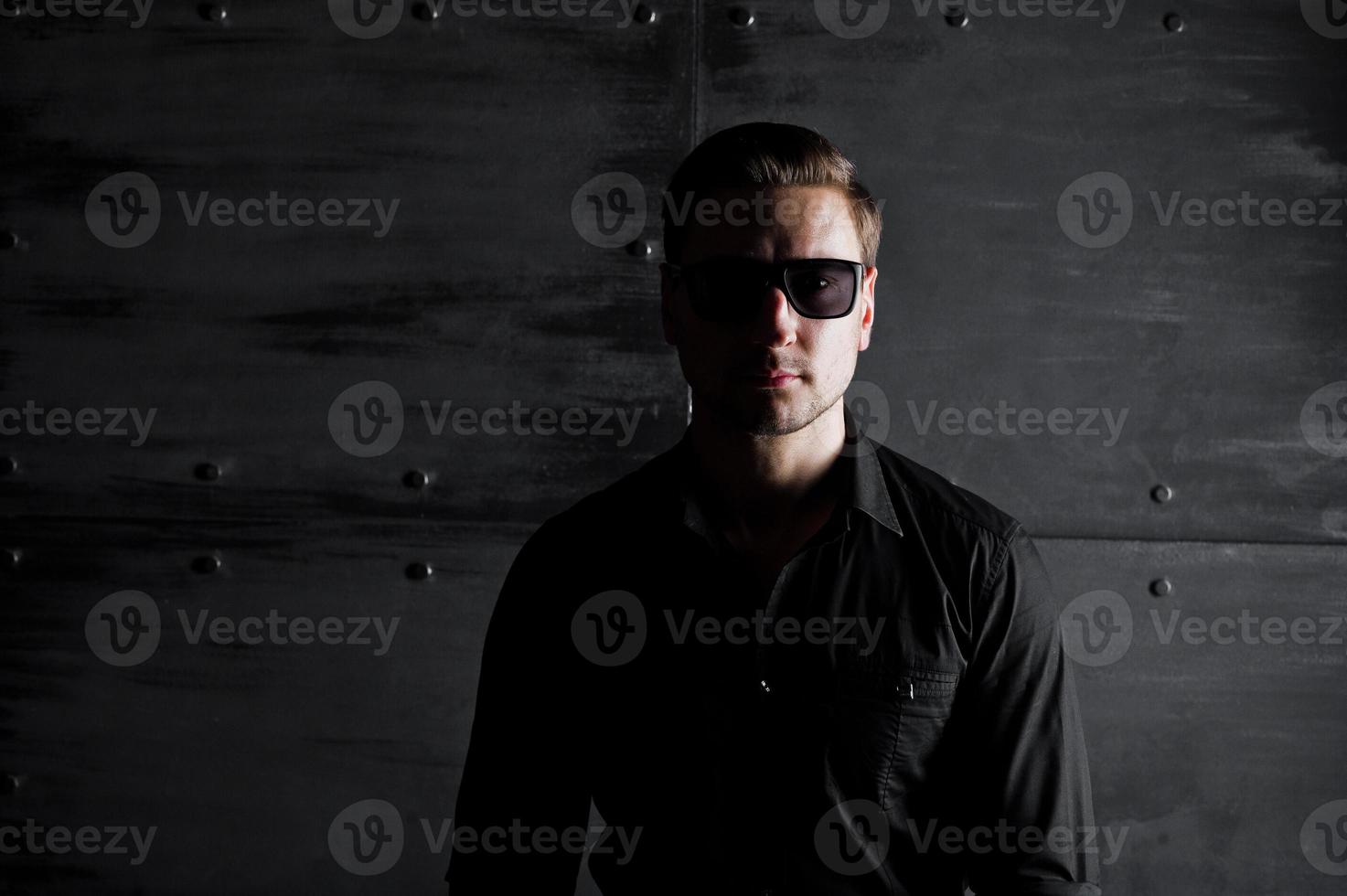 retrato de estudio de hombre elegante vestido con camisa negra y gafas contra la pared de acero. foto