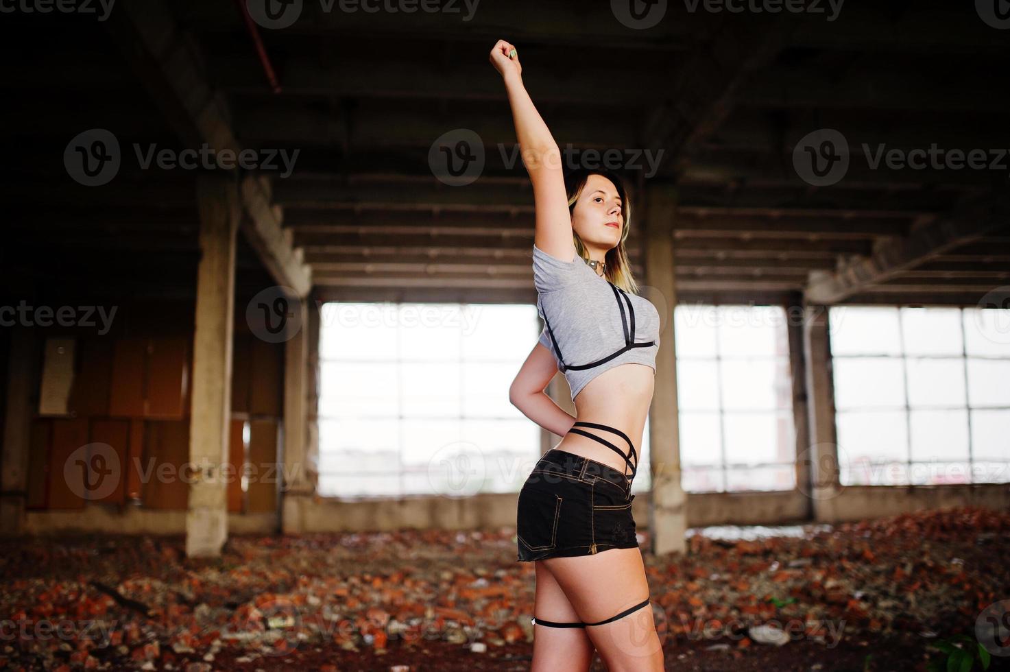 Girl wear on shorts and black erotic fetish underwear at abadoned factoty with brick. photo