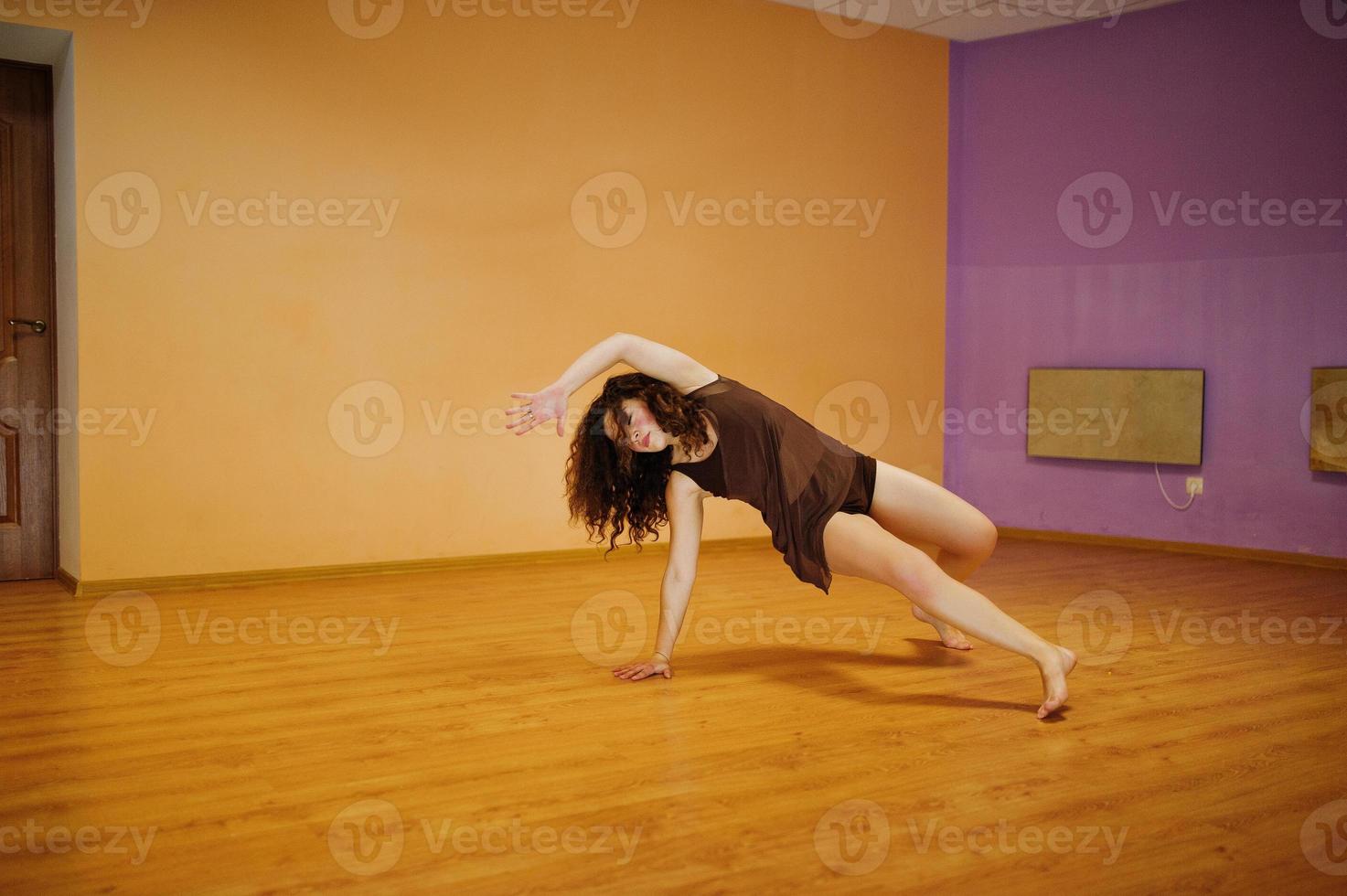 Curly brunette plus size model doing acrobatic at dance room. photo