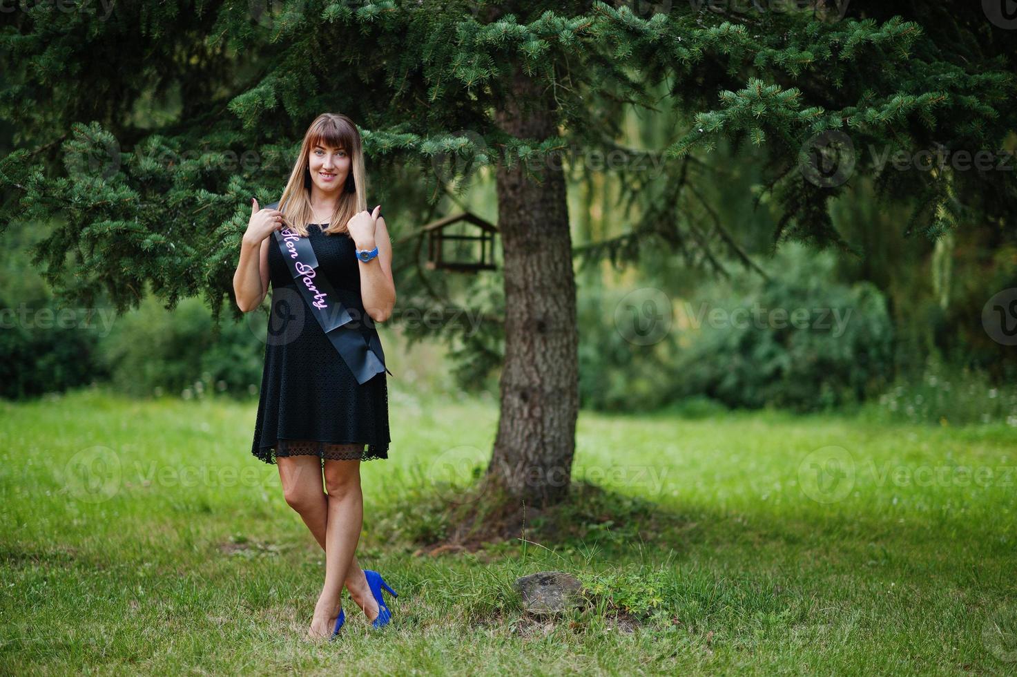 Portrait of gorgeous girl wear on black at hen party, posed at park. photo