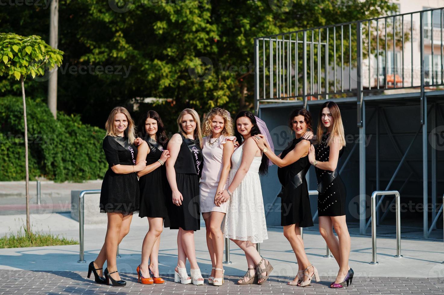 Group of 7 girls wear on black and 2 brides at hen party. photo