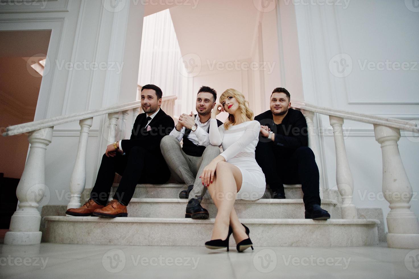 Three stylish bearded man well dressed with one blonde girl in white dress posed. Musician band or singers. photo