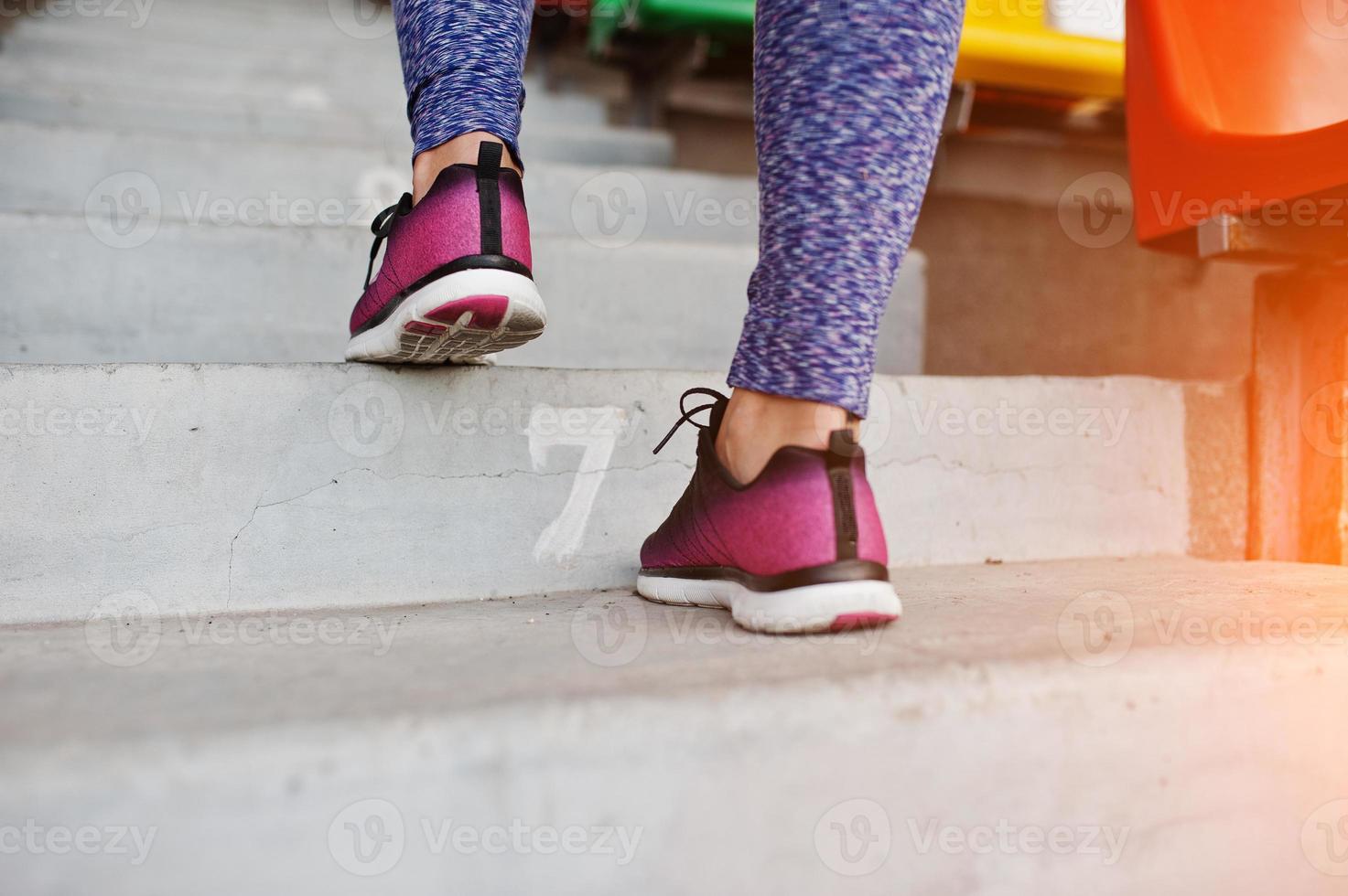 Active young woman running up on stairs in the stadium. photo