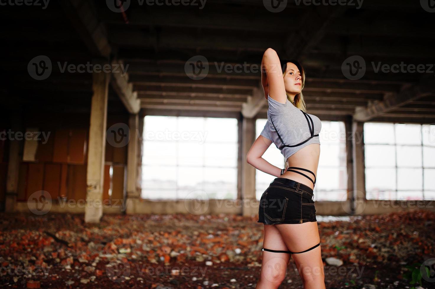 Girl wear on shorts and black erotic fetish underwear at abadoned factoty with brick. photo