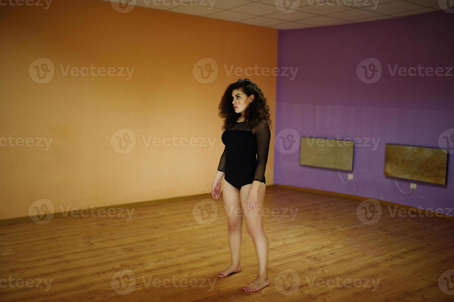 modelo morena rizada de talla grande haciendo acrobacias en la sala de baile. foto