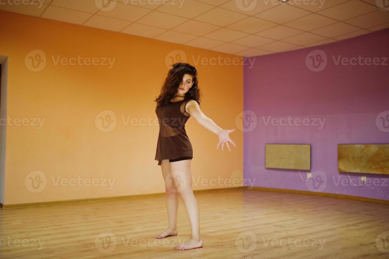 Curly brunette plus size model doing acrobatic at dance room. photo