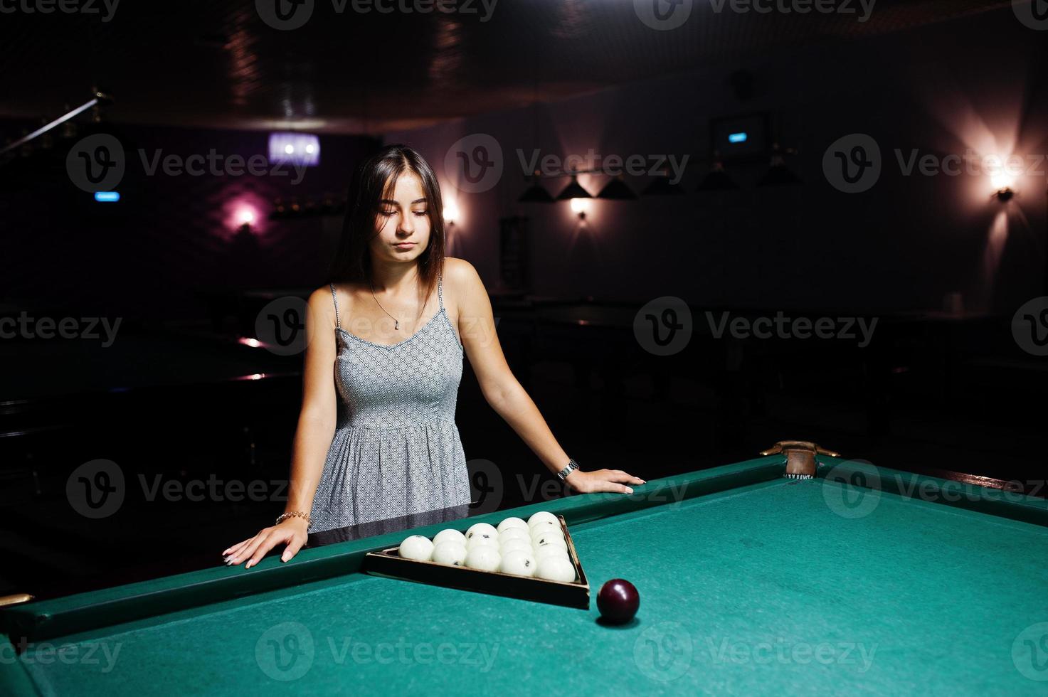 Portrait of a stunning woman standing next to the billiards table. photo