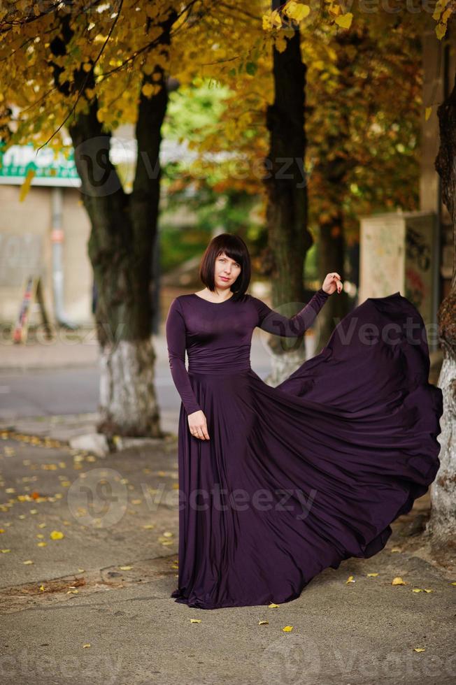 mujer morena adulta en vestido violeta sobre fondo de otoño. foto