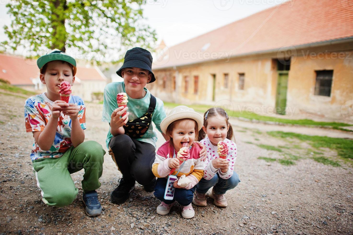 Four funny children eat ice cream outdoor. photo
