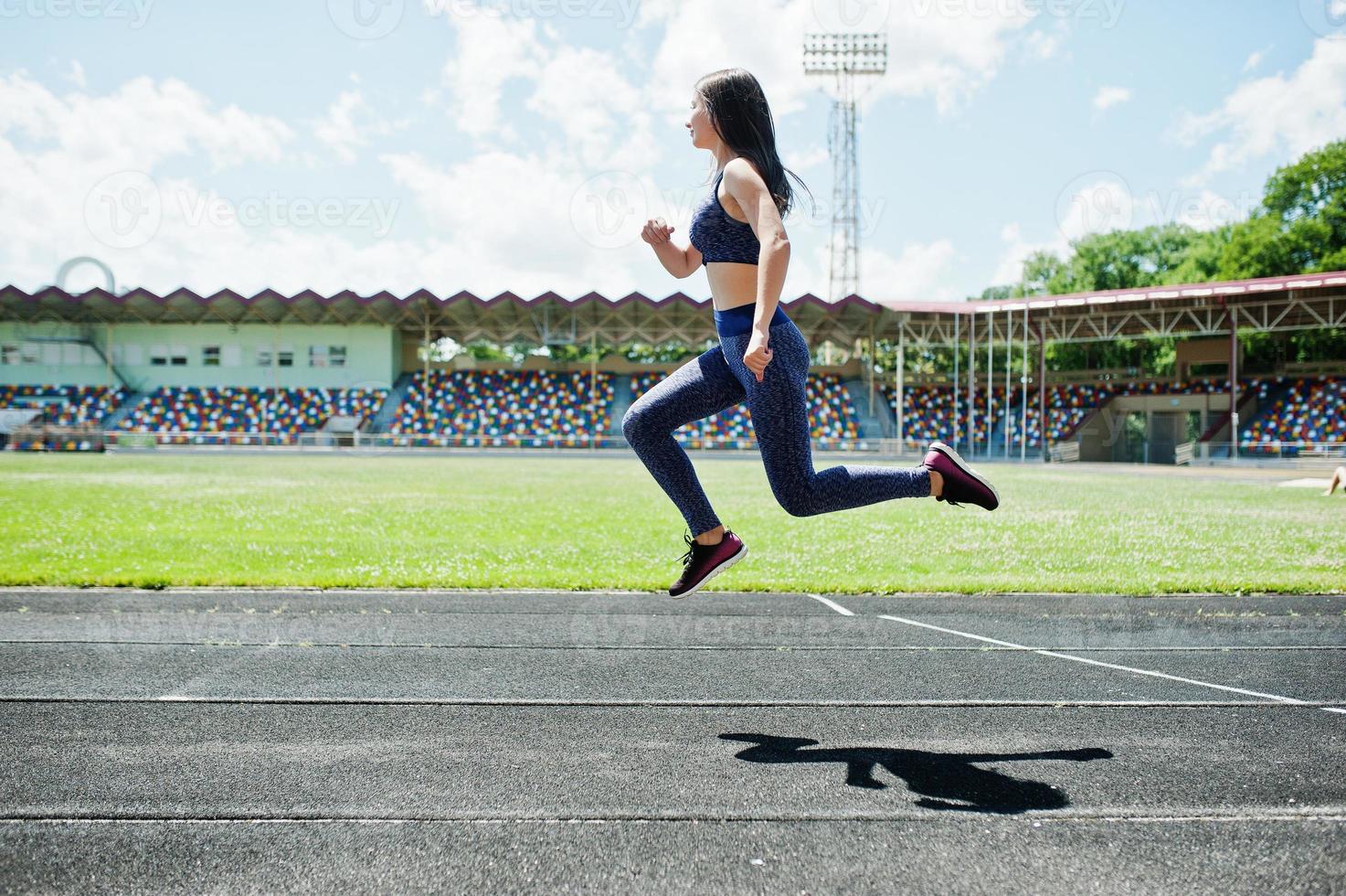 Portrait of a strong fit girl in sportswear running in the stadium. photo