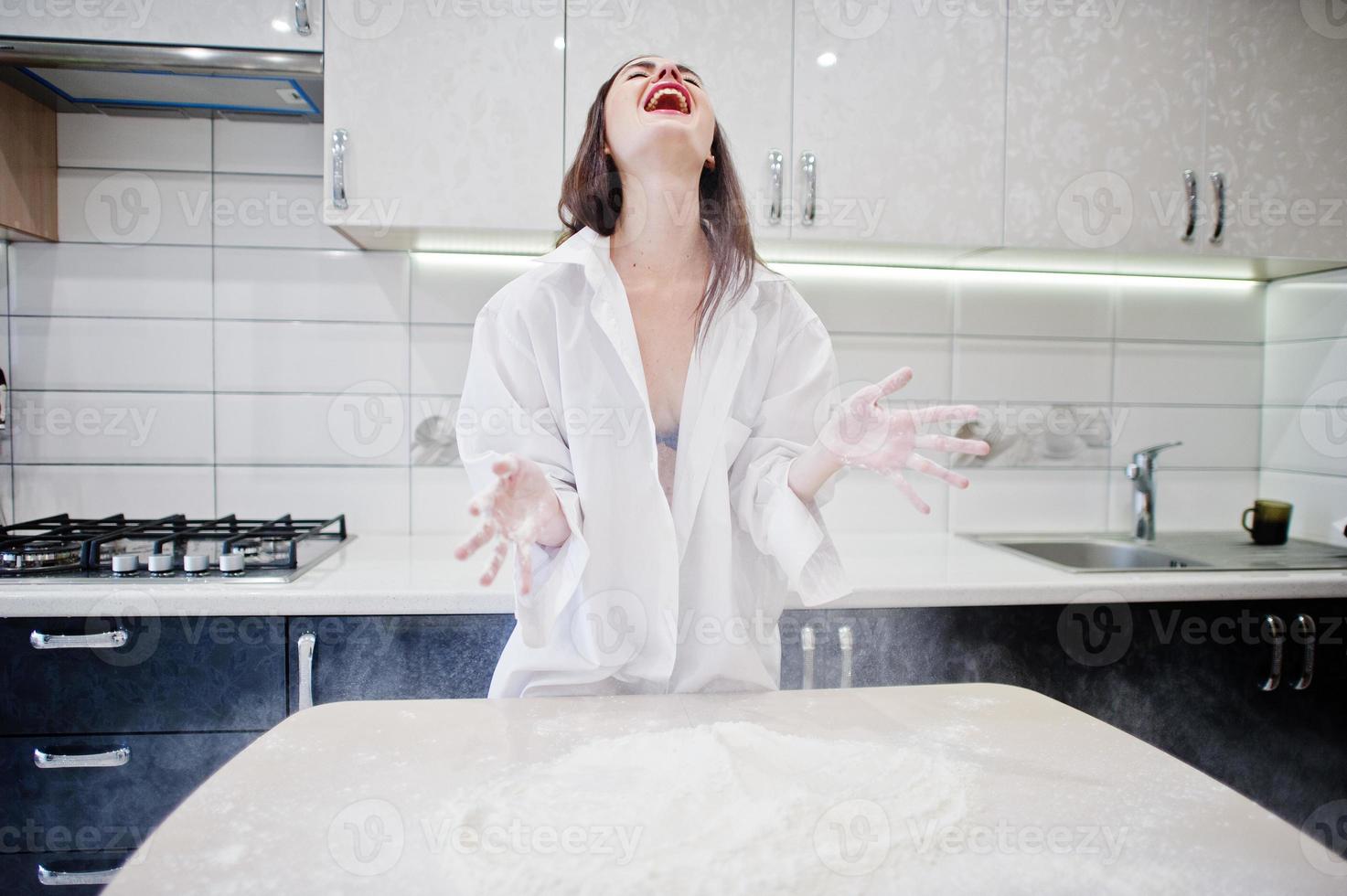 Brunette girl, wear at shirt and underwear play with flour at the white kitchen. photo