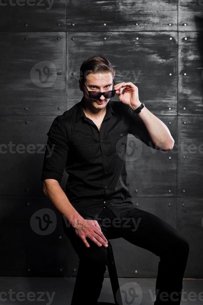 retrato de estudio de hombre elegante vestido con camisa negra y gafas contra la pared de acero. foto