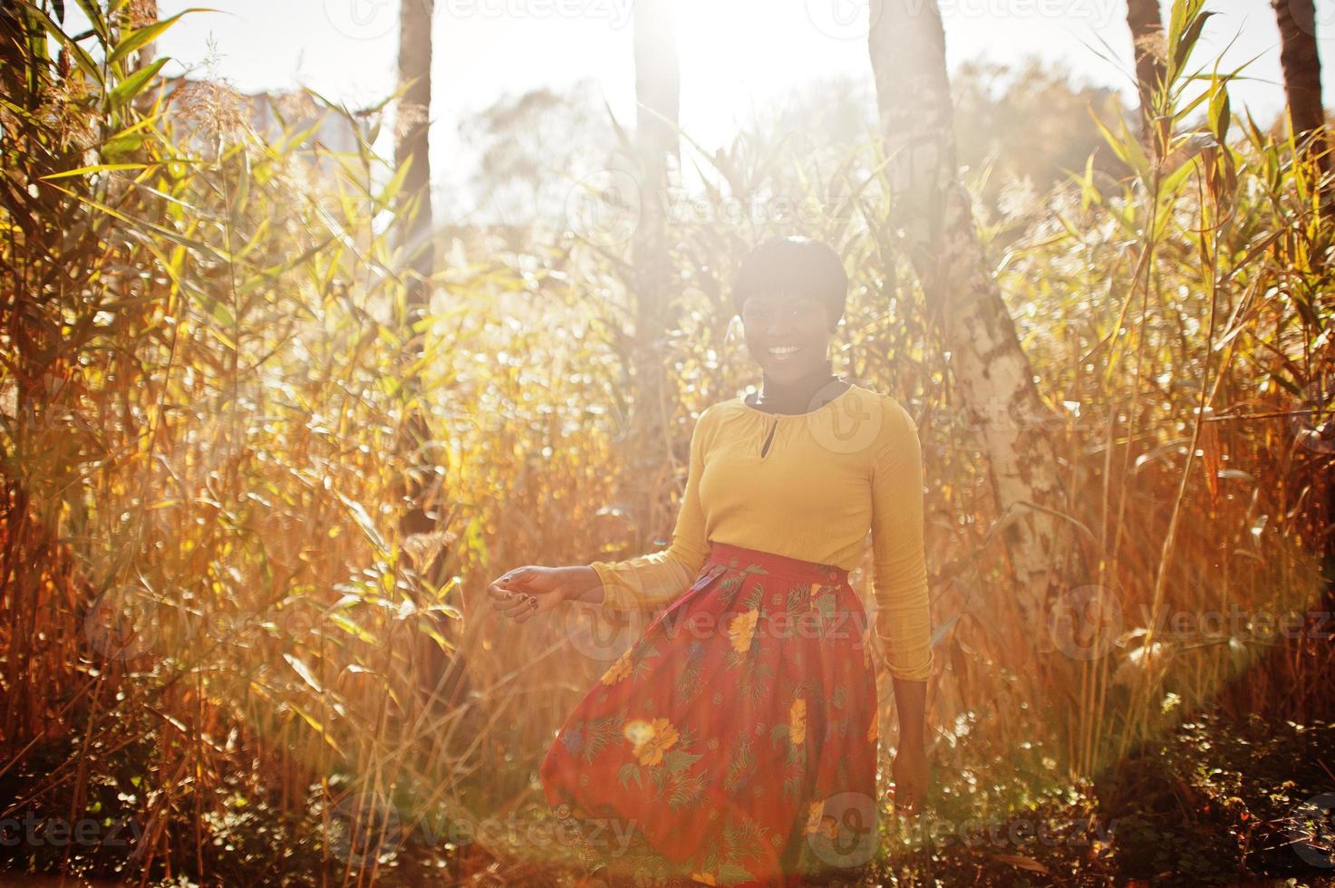 African american girl at yellow and red dress at golden autumn fall park. photo