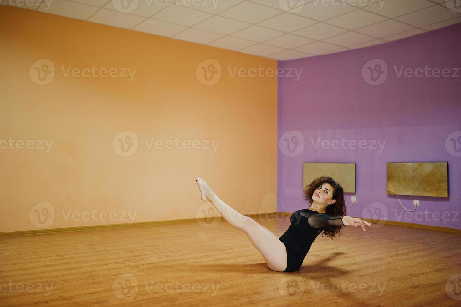 Curly brunette plus size model doing acrobatic at dance room. photo