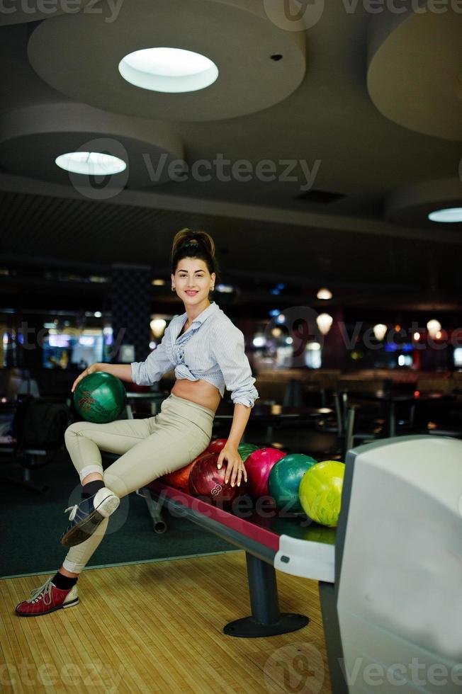 Girl with bowling ball on alley played at bowling club. photo