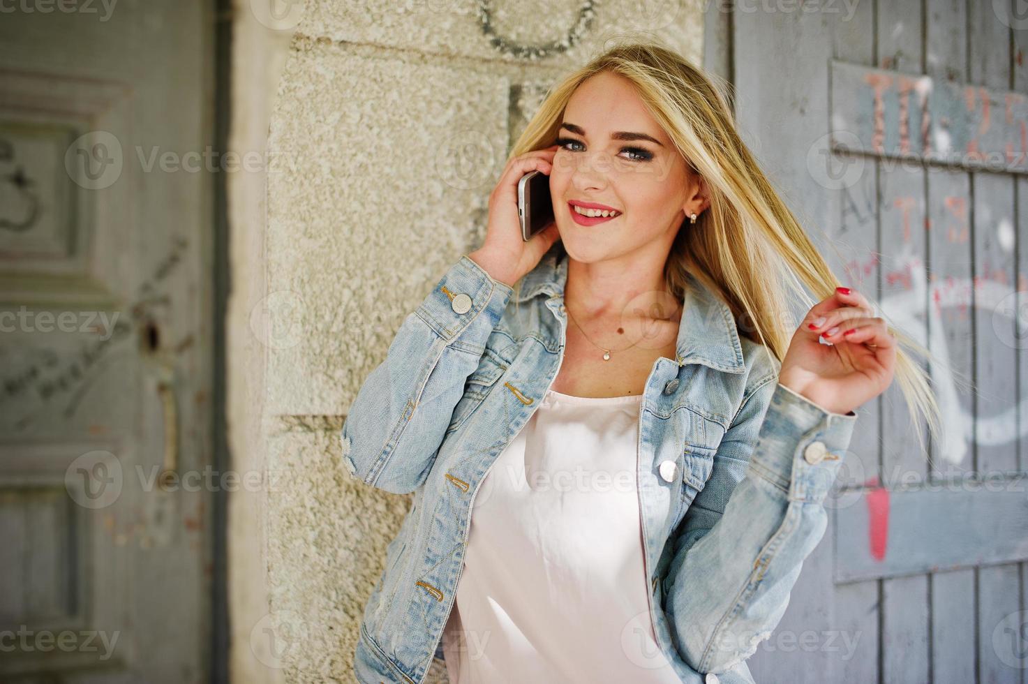 desgaste de chica rubia en chaqueta de jeans planteada en la calle. foto