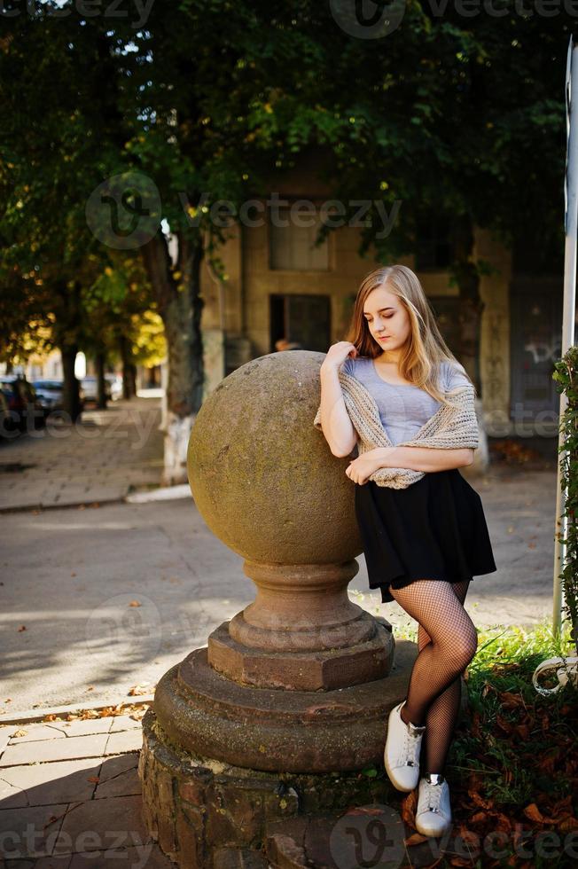 Young blonde girl in black skirt with scarf posed at street of city. photo