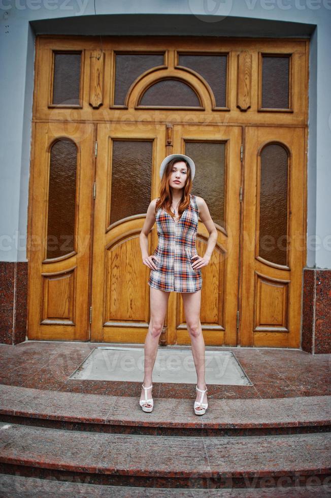Amazing long legs with hig heels girl wear on hat posing against large wooden doors. photo
