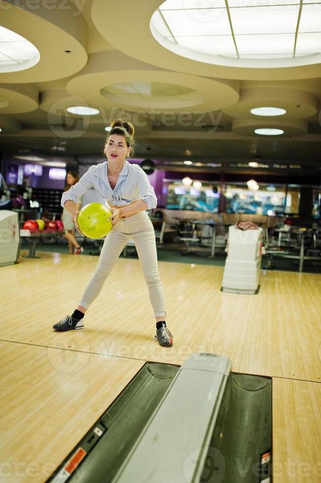 Girl with bowling ball on alley played at bowling club. photo