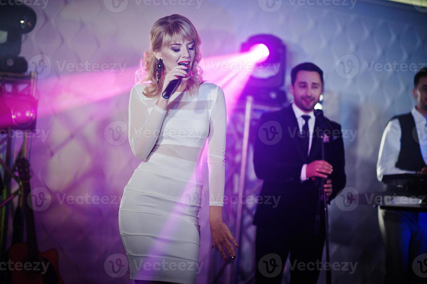 Musicial music live band performing on a stage with different lights. Beautiful blonde vocal singer girl. photo